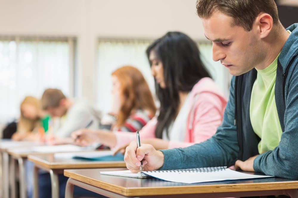 Side view of a group of young students writing notes in the classroom